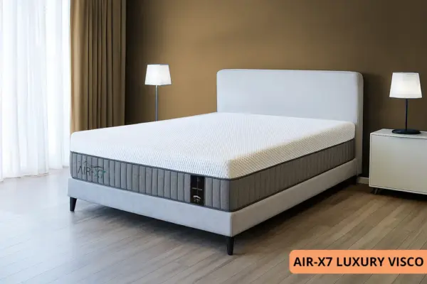 מזרן LUXURY VISCO מסדרת AIR-X7 עם מיטה סגנונית בחדר מעוצב עם קיר בצבע חום בהיר ווילונות בצבע חום בהיר