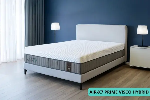 מזרן PRIME VISCO HYBRID מסדרת AIR-X7 עם מיטה סגנונית בחדר מעוצב עם קיר כחלחל ווילונות אפורים עם גוון כחלחל