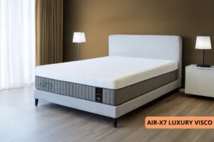 מזרן LUXURY VISCO מסדרת AIR-X7 עם מיטה סגנונית בחדר מעוצב עם קיר בצבע חום בהיר ווילונות בצבע חום בהיר