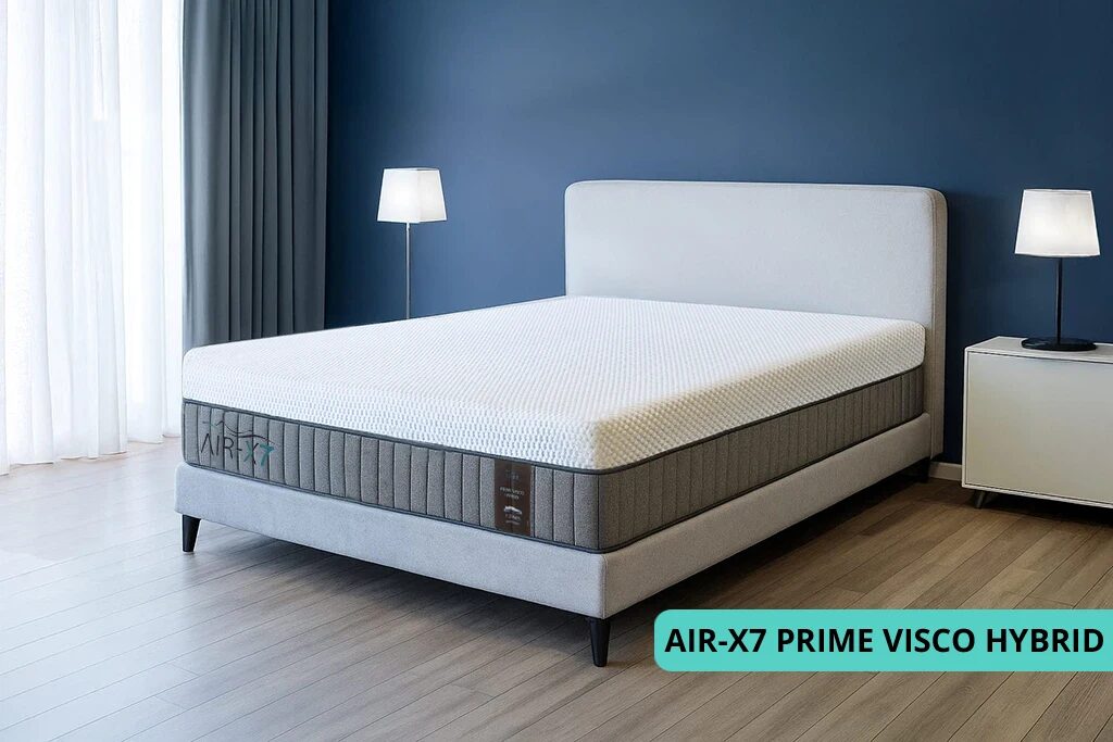 מזרן PRIME VISCO HYBRID מסדרת AIR-X7 עם מיטה סגנונית בחדר מעוצב עם קיר כחלחל ווילונות אפורים עם גוון כחלחל